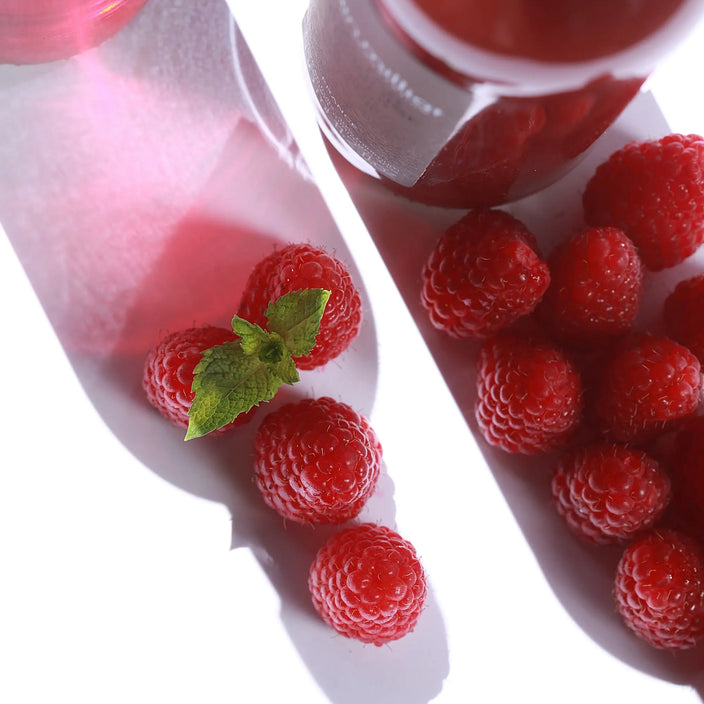 Visuel avec des framboises qui prennent la forme d'une bouteille de pétillante rhubarbe AM et de la boisson rhubarbe Alain Milliat